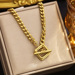 Macro shot of gold plated thick Cuban chain necklace with a square geometric clasp