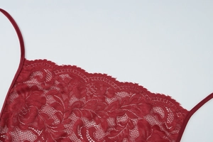 Detail of dark red lace dress featuring floral patterns and delicate eyelash edges