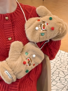 Détail de moufles teckel en peluche avec pompons festifs et cordon de cou