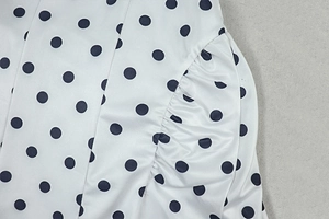 Close-up of black polka dot pattern on white fabric with pleated stitching detail