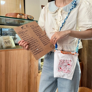 Détail d'un mini sac en toile avec broderie cerise et bandoulière en corde tressée
