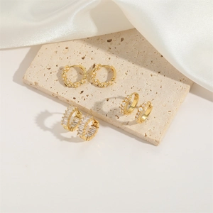 Detailed view of three gold vintage hoop earrings with pearls and zircon on marble stone