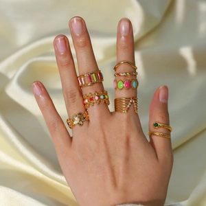 Macro shot of 18K gold plated rings with colorful enamel on soft silk background