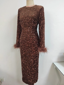 Détail d'une robe de soirée marron café à paillettes avec poignets en plumes et manches longues