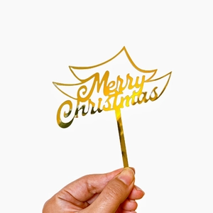 Detailed view of shiny gold acrylic Merry Christmas cake topper with cursive lettering