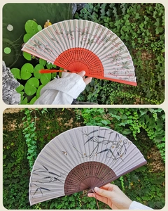 Detailed view of hand-held folding fans with floral cherry blossoms and bamboo ink patterns