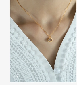 Close-up of elegant gold necklace with circular gemstone pendant on lace clothing