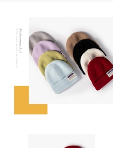 Flat lay of colorful knit beanies featuring wide folded brims and letter patches