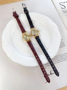 Close-up of vintage gold women watches with black and brown leather straps on magazines