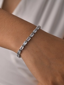 Close-up of sparkling emerald-cut zircon tennis bracelet worn on a woman's wrist