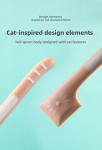 Macro detail of the cat-themed pink feeding spoon featuring a unique tail-shaped handle