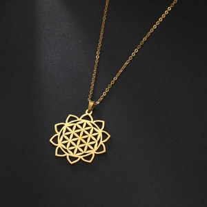 Close-up of golden stainless steel hollow flower of life pendant on black background