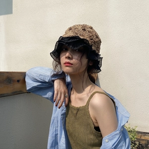 Detail of straw sun hat with lace trim and hollow design paired with checkered shirt