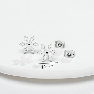Macro detail of 12mm silver snowflake stud earrings with polished steel texture