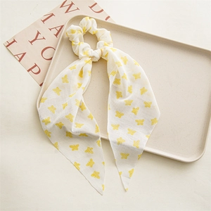 Detail view of a white chiffon hair scrunchie with yellow butterfly patterns on a tray