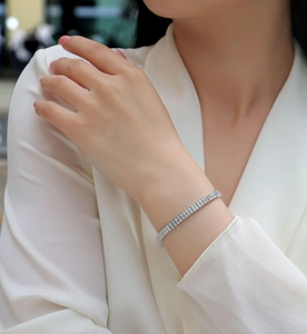 Close-up of three-row silver tennis bracelet with sparkling stones on model wrist