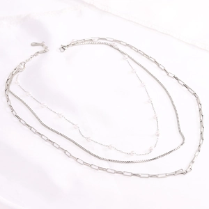 Detail of triple-layer silver necklace with pearls and diverse chain textures