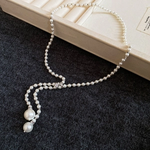 Detailed view of pearl Y-necklace with silver beads and tassel drop pendants
