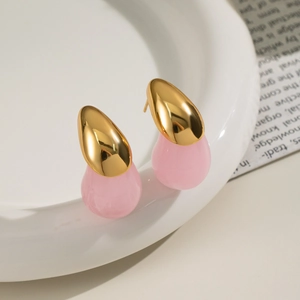 Detailed view of fashion teardrop earrings with gold metal and pink resin on ceramic tray