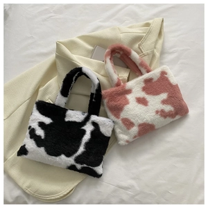 Detail of plush tote bags in black, white, and pink cow patterns on a beige blazer