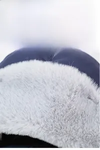 Close-up of winter trapper hat showing thick grey plush lining and blue windproof fabric