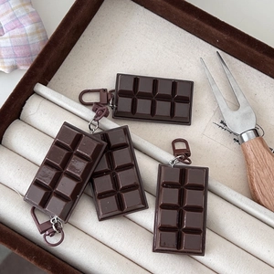 Detailed view of dark brown chocolate shaped charms on a velvet jewelry tray display