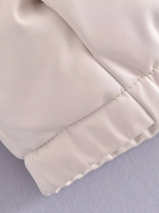Makrodetail der cremeweißen PU-Ledertextur mit feinen Nähten und elastischem Saumdesign