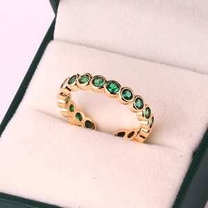Detail of 18k gold plated ring featuring row of green cubic zirconia in jewelry box