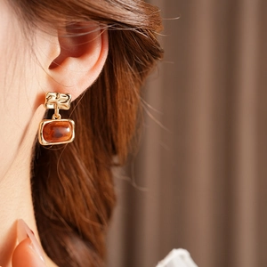 Gros plan de boucles d'oreilles carrées en résine ambrée plaquées or sur un modèle
