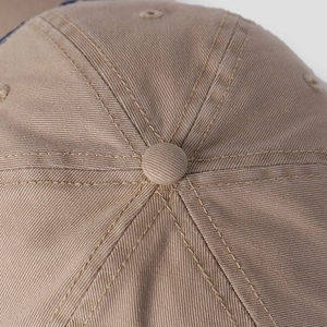 Macro detail of khaki baseball cap featuring six-panel stitching and top fabric button