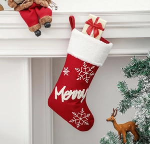 Red Christmas stocking with snowflake embroidery and Merry text hung on fireplace