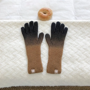 Detail of gradient knitted gloves with leather patch on cozy white textured background