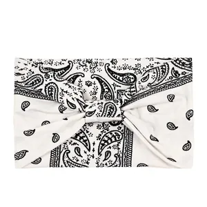Detail of white paisley yoga headband with wide stretch fabric and central twist knot