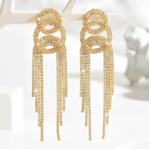 Macro shot of gold tassel drop earrings with sparkling rhinestones and triple-ring detail