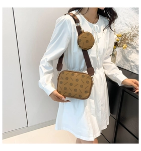 Brown monogram crossbody camera bag set shown on model in white dress on neutral background