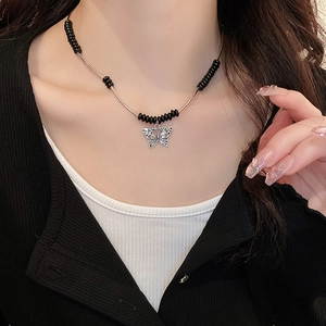 Detail of silver hollow butterfly pendant with black beaded necklace on model