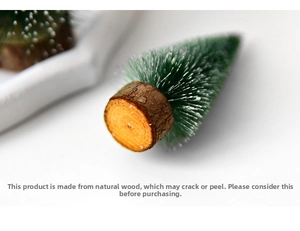 Close-up of mini Christmas tree with snow-flocked branches and a natural wooden base