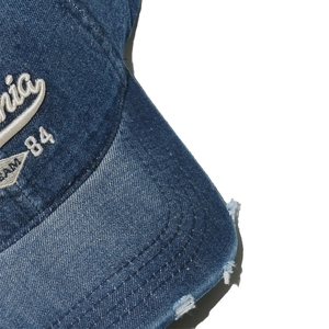 Detailed macro view of vintage washed navy denim fabric with 3D embroidery and distressed brim