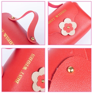 Detail view of red PU leather jewelry handbag with gold floral accents and metal rivets