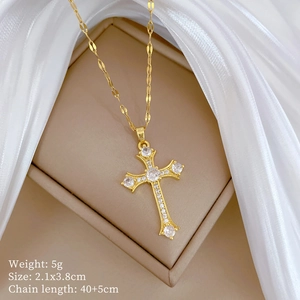Close-up of gold cross necklace with sparkling zircon crystals on elegant white silk