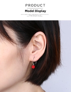 Close-up of a red crystal pavé ball earring on a model showing dangle style and scale