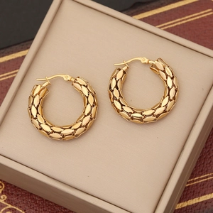 Detailed macro view of gold round earrings with textured woven metal mesh and vintage finish
