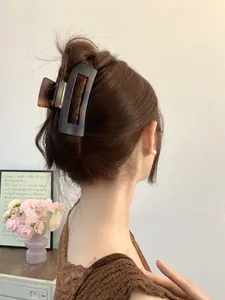 Detail of dark tortoiseshell rectangular hair claw clip worn on a brown bun hairstyle