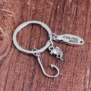 Silver metal fish hook keychain with Love You Dad engraved tag on dark wood surface