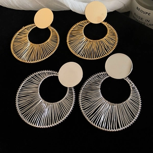 Detail of gold and silver hollow circular drop earrings with textured metal weave