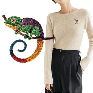 Macro shot of colorful crystal lizard brooch and model wearing it on beige clothing