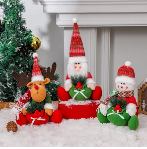 Detailed view of sitting plush Santa, reindeer and snowman dolls on a white snow surface