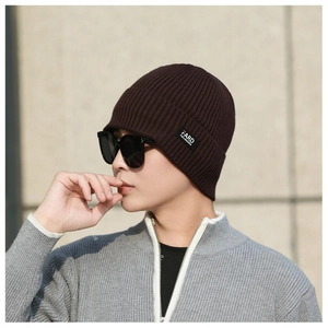 Detail of dark brown ribbed knit beanie featuring a premium black fabric side label