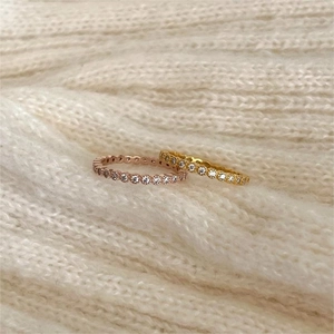 Detail of 925 silver eternity rings with cubic zirconia on a knit sweater surface