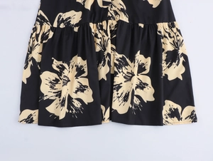 Close-up detail of pleated hem with beige floral prints on a black woven dress